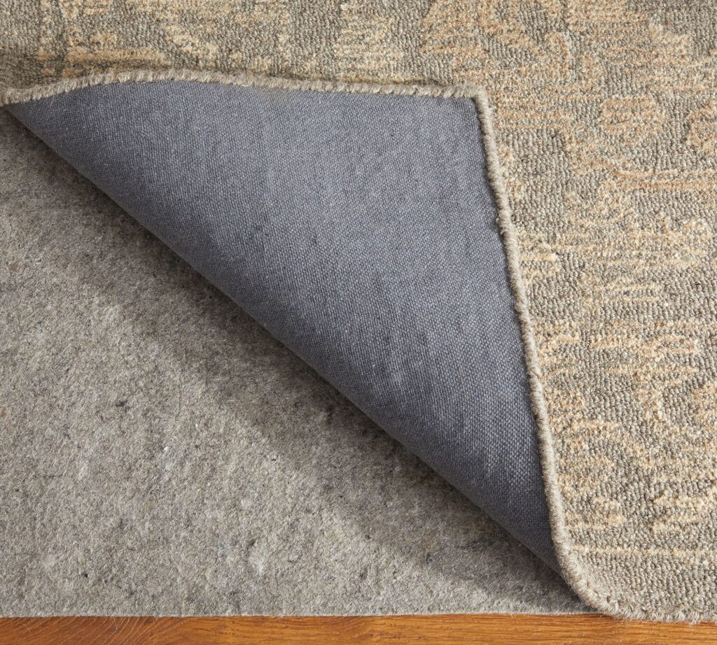 Close-up of a Pottery Barn rug pad under a beige woven rug, featured in our affordable rugs in NYC guide.