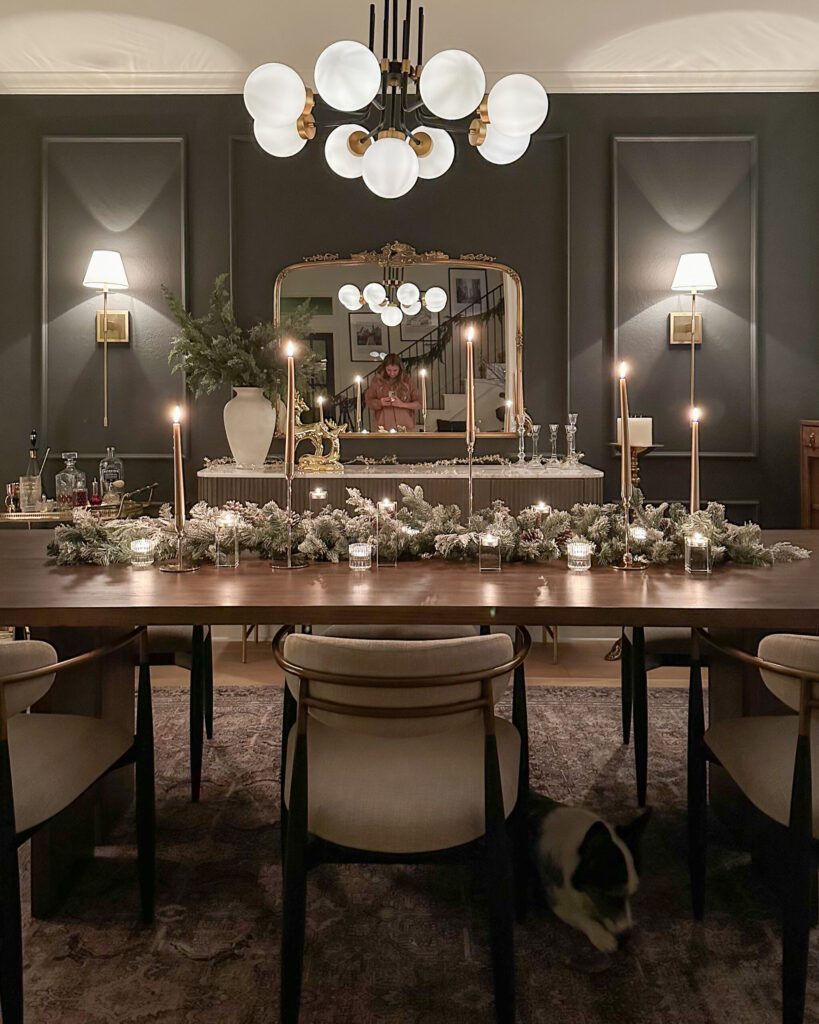 Holiday table set with candlesticks, pinecones dusted in snow, and layered lighting.