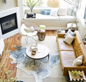 Cowhide rug layered over a neutral area rug creating contrast and visual interest.