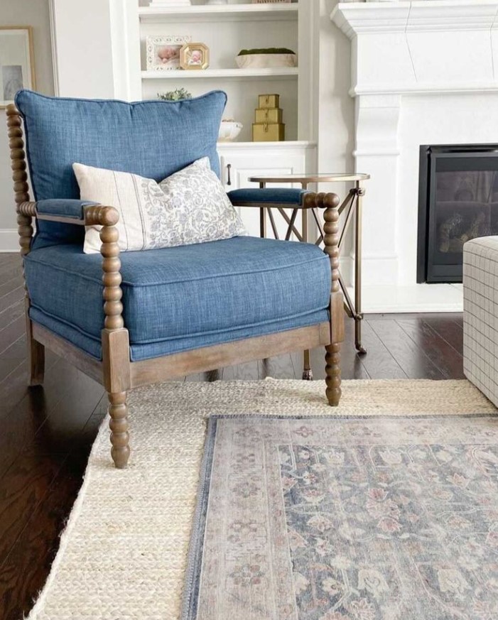 Neutral area rug layered beneath a smaller contrasting rug in a living room.