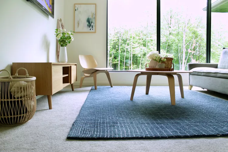 Rug layered over plush carpeting with visible bubbling and uneven edges.