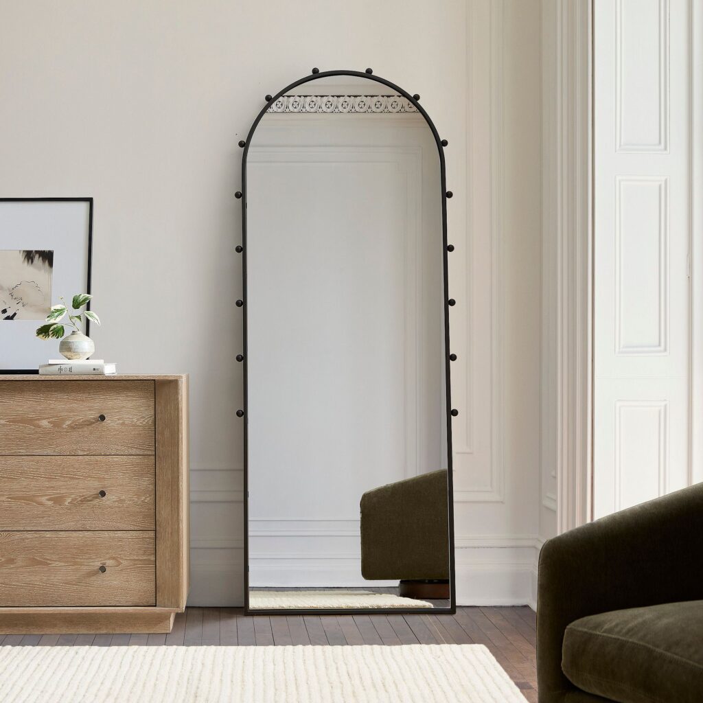 Modern living room with large floor mirror leaning against the wall.